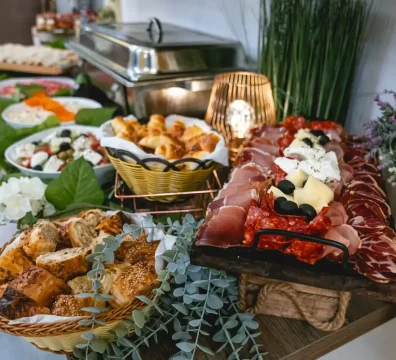 Švedski sto za roditelje sa keteringom koji je ukrašen veštačkim cvećem i zelenilom. U ponudi je: bogato predjelo,